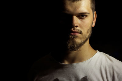 Close-up portrait of young man against black background