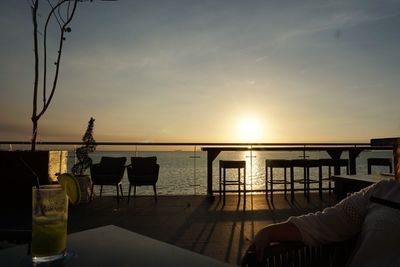 Chairs and table on beach against sky during sunset