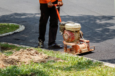 Low section of manual worker with machinery working on road