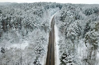 High angle view of empty road amidst snow covered landscape in forest