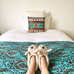 Low section of woman wearing footwear on bed at home