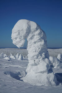 Frozen sea against clear blue sky during winter