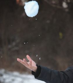 Cropped hand throwing snow ball during winter