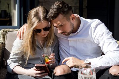 Young couple looking at mobile phone while sitting outdoors