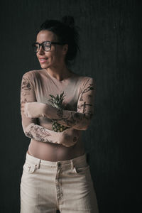 Portrait of young woman standing against black background