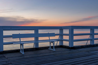 Chairs on beach against sky during sunset