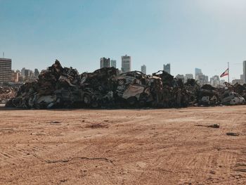 Stack of destroyed cars by buildings against sky