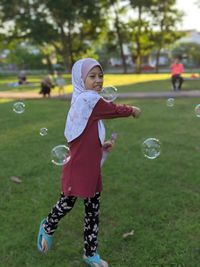 Full length of girl playing with bubbles in park