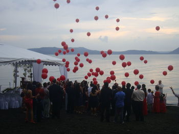 Rear view of people with balloons against calm lake
