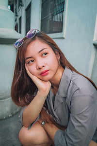 Young woman looking away while crouching in city