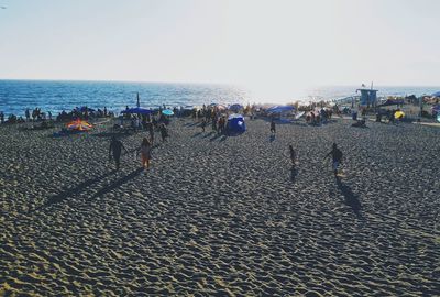 Group of people on beach against clear sky