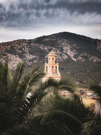 A church tower in a mediterranean town against mountains and sky