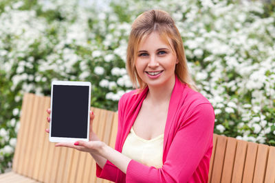 Portrait of smiling young woman using smart phone outdoors