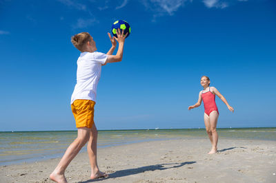 Full length of boys on beach against sky