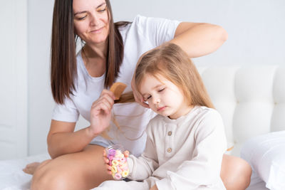 Smiling mother combing hair of daughter