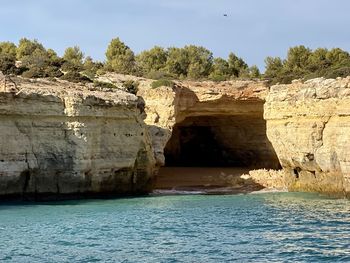 Rock formation by sea against sky