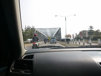 Vehicles on road against sky seen through car window