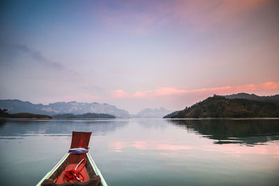 Cropped image of longtail boat moored at river against sky