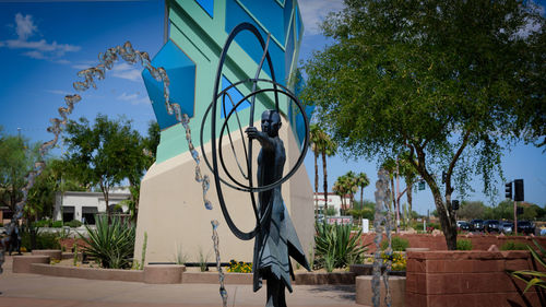 Full length of woman on footpath in city against blue sky