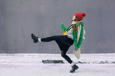 Side view of woman dancing on snow covered wall