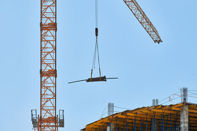 Low angle view of crane against clear blue sky