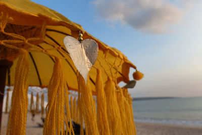 Close-up of yellow umbrella on beach against sky