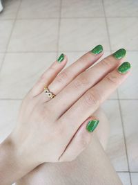 Close-up of woman hand with tattoo on tiled floor