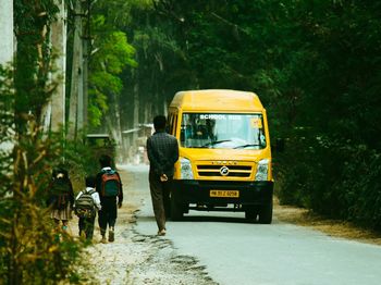 Rear view of people walking on road in city