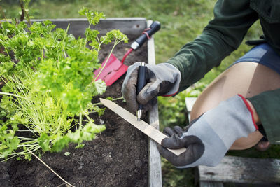 Midsection of woman writing label for plant in urban garden