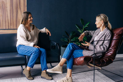 Two modern stylish women are sitting in the office discussing ideas and implementation of plans. 