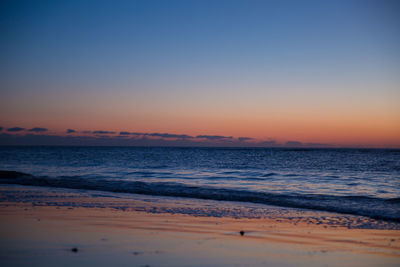 Scenic view of beach against clear sky at sunset