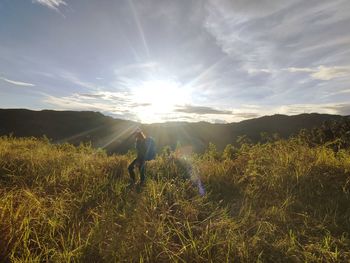 Rear view of woman standing on field against sky