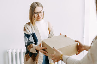 A girl receives a parcel from a courier, delivery, order, box, online shopping, millennial, hipster,