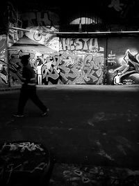 Side view of man with graffiti on wall at night