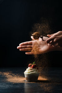 Midsection of man holding ice cream against black background