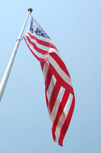 Low angle view of american flag against clear blue sky