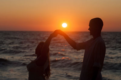 Friends standing on beach during sunset