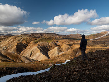 Man standing on rock against sky