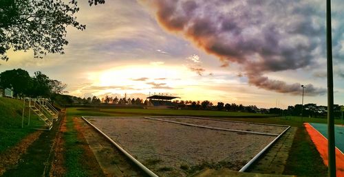 Scenic view of field against dramatic sky during sunset