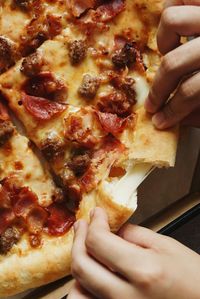 Close-up of hand holding pizza