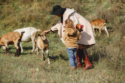 Mother and daughter standing with goats