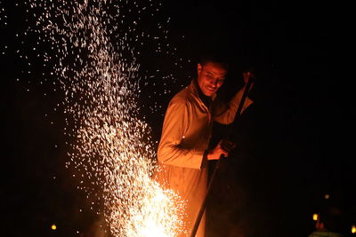 Side view of young man standing against black background