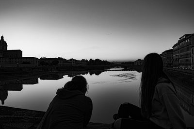 Rear view of people looking at lake against clear sky