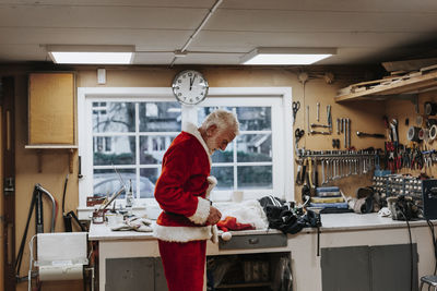 Senior man putting santa costume on