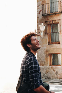 Side view of young man standing against wall