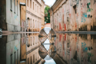 Close-up of crystal ball in puddle against building