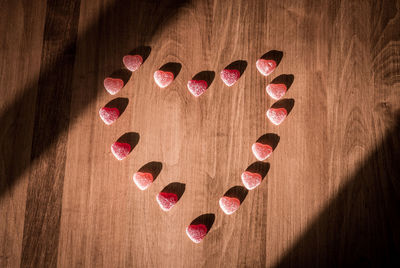 Directly above shot of candies arranged in heart shape on hardwood floor
