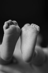 Close-up of baby feet against black background