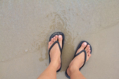 Low section of bare feet on sand