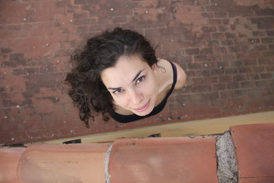 Portrait of woman against brick wall